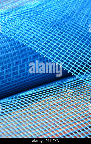 Close-up texture of a blue reinforcing mesh rolled up in a roll. Building resource for reinforcing walls in the process of their warming Stock Photo