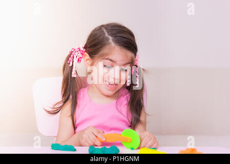 Portrait of Cute girl playing with toys for playdough near table. Selective focus and small depth of field. Stock Photo