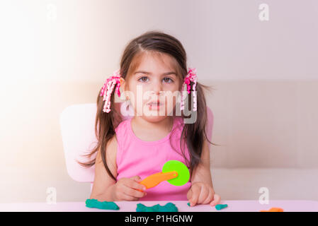 Portrait of Cute girl playing with toys for playdough near table. Selective focus and small depth of field. Stock Photo