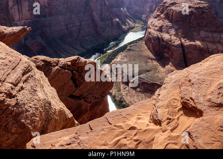 Footprints on the edge of cliff Horseshoe Bend Utah and Arizona.  The Colorado river carves its way through the red and orange sandstone Canyon Stock Photo