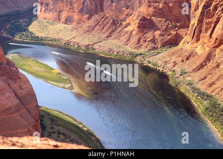 Boat tour on the Colorado river photo taken from the ridge of Horseshoe Bend National Park. The pink, red and orange sandstone canyon walls in Arizona Stock Photo