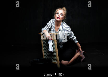 Beautiful housewife woman doing laundry on black background with copy space Stock Photo