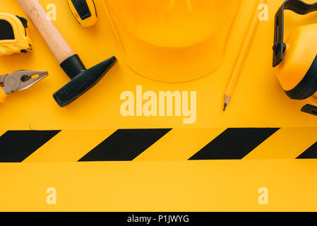 Under construction concept with yellow protective helmet and tools, top view flat lay minimalistic composition Stock Photo