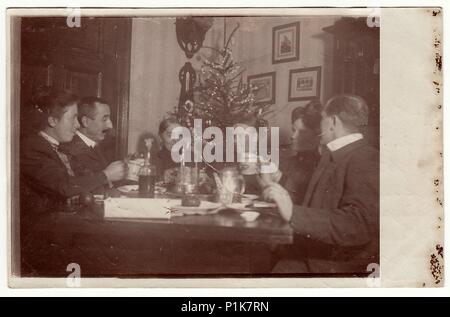 GERMANY - CIRCA 1940s: Vintage photo shows family sits at the table during Christmas time. In the room is a Christmas tree. 1940s Stock Photo