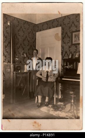 GERMANY - CIRCA 1930s: Vintage photo shows women pose at home. In the picture are piano and stove. Black & white antique photography. 1930s Stock Photo