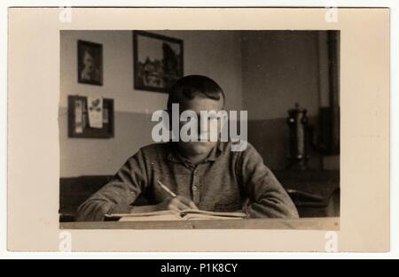 EILENBURG, GERMANY - CIRCA 1940s: Vintage photo shows young boy (pupil, student) sits at the classroom. Black & white antique photography. Stock Photo