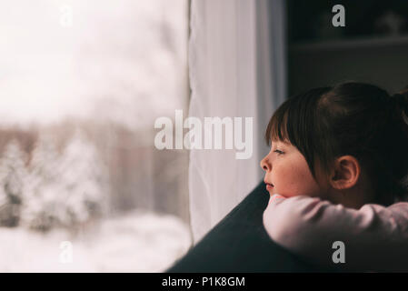 Girl looking out of a window in winter Stock Photo
