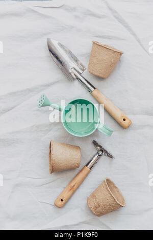 Watering can, gardening tools and flower pots on linen tablecloth Stock Photo