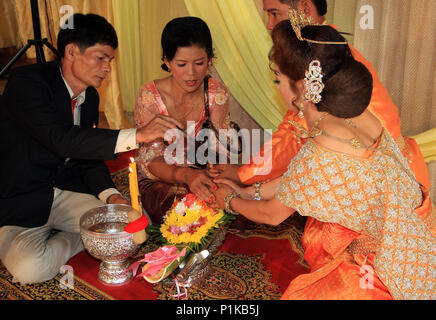 At a Khmer wedding the father and mother of the bride sanctify the marriage union by holding hands and sprinkling water over the joined hands. Stock Photo