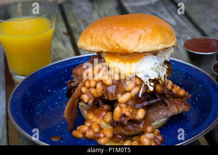 Sausage,Egg,Streaky Bacon and baked beans served in a brioche bun for Breakfast Stock Photo