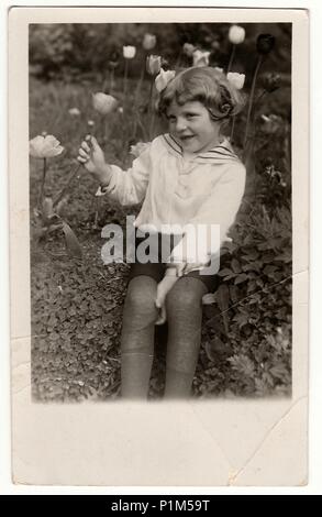GERMANY - CIRCA 1950s: Vintage photo shows cute girl holds the tulip. Black & white antique photography. Stock Photo