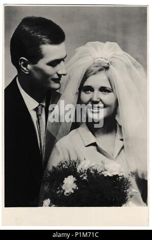 BRATISLAVA, THE CZECHOSLOVAK SOCIALIST REPUBLIC - DECEMBER 11, 1965: Retro photo shows bride wears a white veil and groom wears a dark suit.  Black & white vintage photography of wedding couple. Stock Photo
