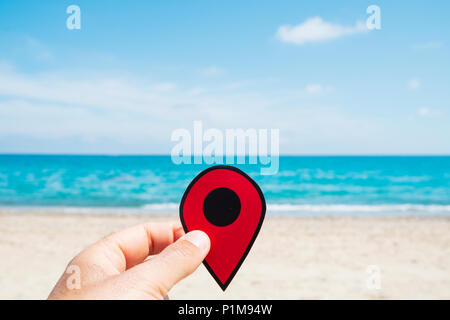 closeup of a young caucasian man with a red marker in his hand, relaxing on the beach, with the sea in the background Stock Photo