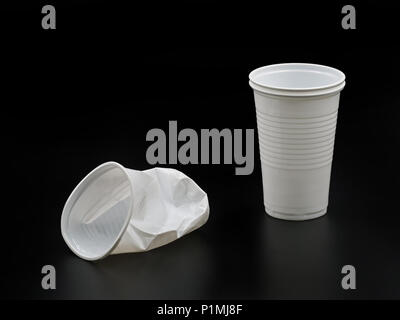 Crushed and new plastic cups isolated on black background. Stock Photo