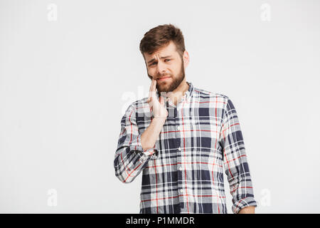 Portrait of a sad young man in plaid shirt having a toothache isolated over white background Stock Photo