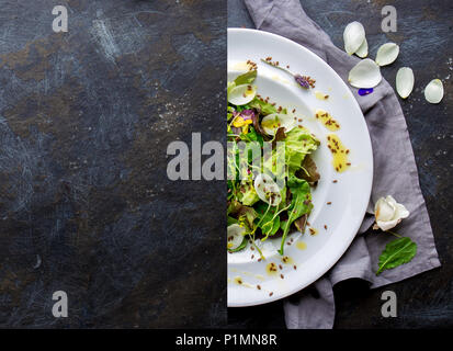 Restaurant menu concept. Collage made from half a restaurant plate with lettuce and edible flowers salad and a blank dark background. Top view. Copy s Stock Photo