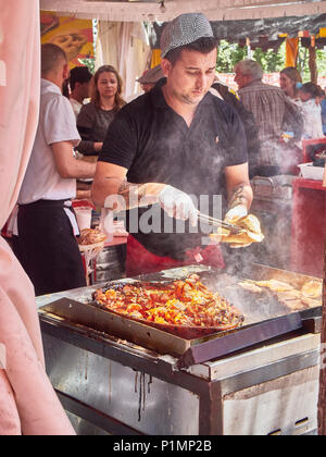 Hispanic cook cooking Pork Tenderloin and Oreja de Cerdo (Pork Ear) on griddle in a stall of a Street Food fair. Stock Photo