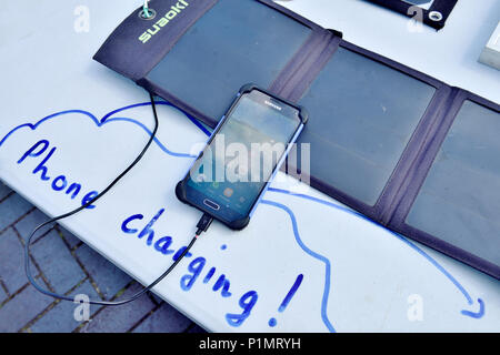 Demonstration of small portable solar panel pack charging a mobile phone Stock Photo