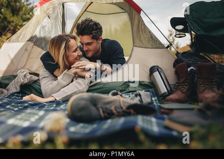 Beautiful young couple lying in a tent. Happy loving couple resting in tent on campsite. Stock Photo
