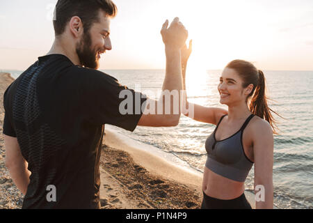 Smiling young couple giving high five while standing at the beach Stock Photo