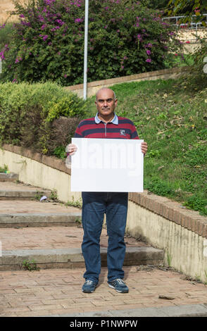 Man holding blank sign in the medieval city of Iglesias, Italy Stock Photo