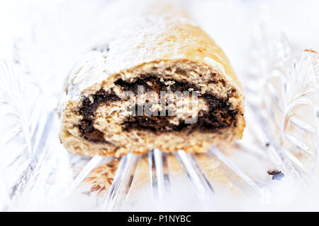 Closeup cut cross section of golden baked whole poppy seed roll cake, or chocolate babka pastry bread on table in crystal glass dish for festive tradi Stock Photo