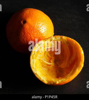 Used orange skins with dramatic light on black background. Square image. Stock Photo