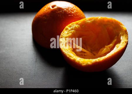 Used orange skins with dramatic light on black background. Horizontal image. Stock Photo