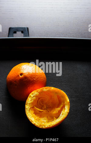 Used orange skins with dramatic light on black background. Vertical image. Stock Photo