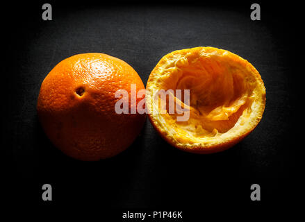 Used orange skins with dramatic light on black background. Horizontal image. Stock Photo