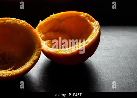 Used orange skins with dramatic light on black background. Horizontal image. Stock Photo