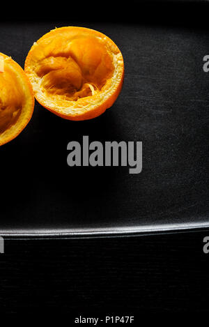 Used orange skins with dramatic light on black background. Vertical image. Stock Photo