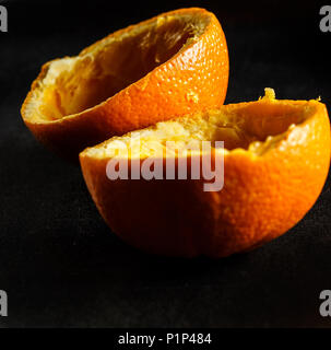 Used orange skins with dramatic light on black background. Square image. Stock Photo