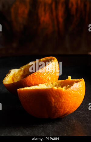 Used orange skins with dramatic light on black background. Vertical image. Stock Photo