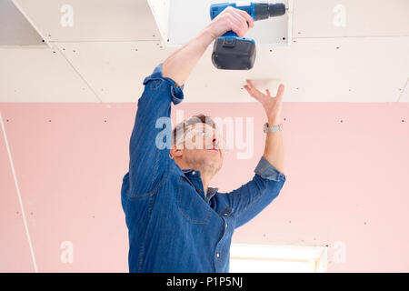 Handyman using cordless drill while working on construction site. Stock Photo
