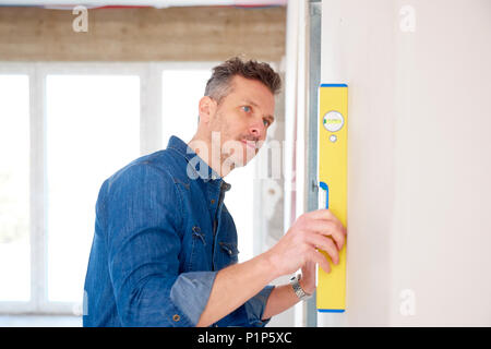 Handyman using spirit level while working on construction site. Stock Photo