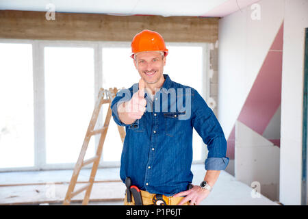 Portrait of smiling handyman wearing safety helmet and showing thumb up while looking at camera and smiling. Stock Photo
