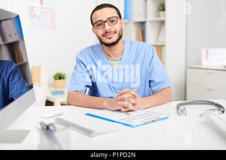Middle-Eastern Doctor Posing at Desk Stock Photo