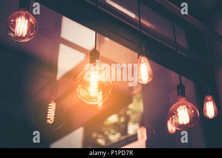 Decorative antique edison style light bulbs against cafe wall background Stock Photo