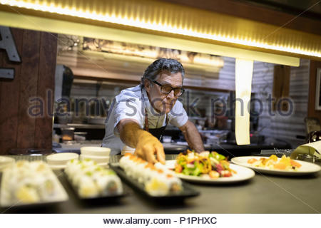 Senior chef plating food in restaurant kitchen
