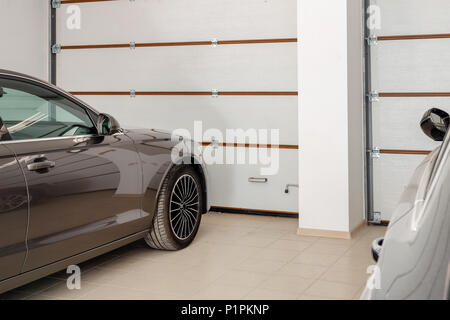 Home garage for two vehicles interior. Clean luxury cars parked at home. Automatic remote control doors. Transport roofed storage. Stock Photo