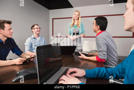 Young millennial businesswoman giving a presentation to other business professionals working in a conference room in a modern place of business Stock Photo