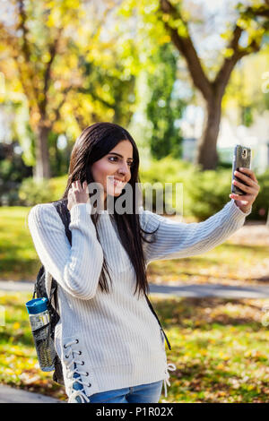 A young female university student of Lebanese ethnicity poses for a self-portrait using her smart phone; Edmonton, Alberta, Canada Stock Photo