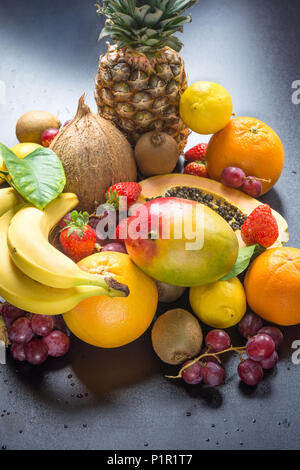 Assortment of Fresh Tropical and Summer Seasonal Fruits Pineapple Papaya Mango Coconut Oranges Kiwi Bananas Lemons Grapefruit Strawberries on Black We Stock Photo