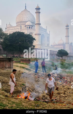 Local men burning garbage on the bank of Yamuna river near Taj Mahal, Agra, Uttar Pradesh, India. Taj Mahal was designated as a UNESCO World Heritage  Stock Photo