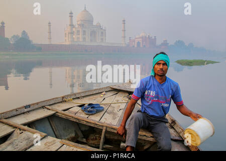 Local man bailing water out of the boat on Yamuna River near Taj Mahal in the morning, Agra, Uttar Pradesh, India. Taj Mahal was designated as a UNESC Stock Photo