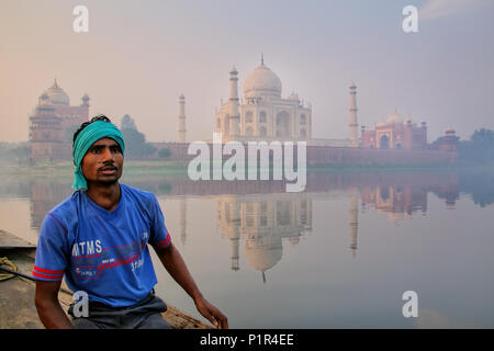 Local man sitting in a boat on Yamuna River near Taj Mahal in early morning, Agra, Uttar Pradesh, India. Taj Mahal was designated as a UNESCO World He Stock Photo