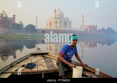 Local man bailing water out of the boat on Yamuna River near Taj Mahal in the morning, Agra, Uttar Pradesh, India. Taj Mahal was designated as a UNESC Stock Photo