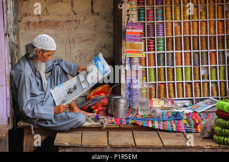 Local man reading newspaper at the street market in Fatehpur Sikri, Uttar Pradesh, India. The city was founded in 1569 by the Mughal Emperor Akbar, an Stock Photo