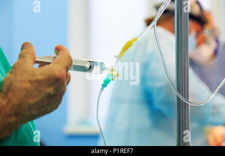 Doctor's hand and infusion drip in hospital on blurred backgroun Stock Photo